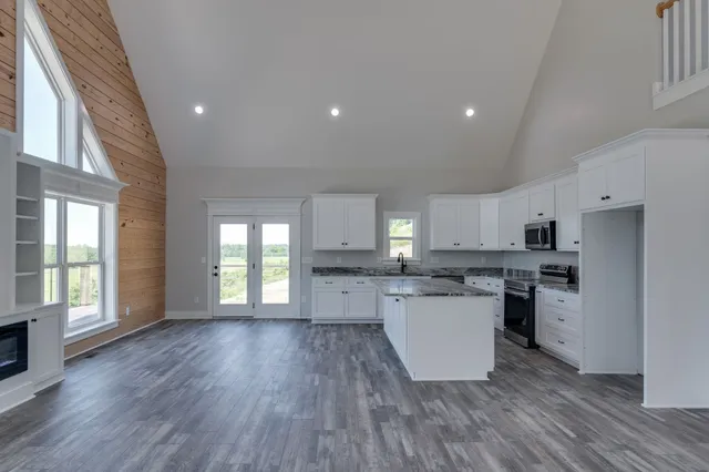 an open kitchen with granite countertop a stove and a wooden floor