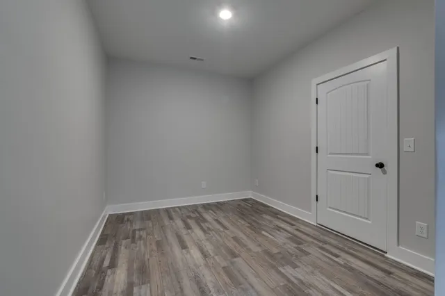 a view of empty room with wooden floor and window