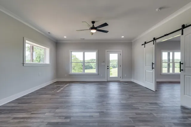 an empty room with wooden floor and windows