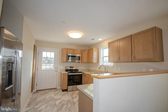 a kitchen with kitchen island granite countertop a sink cabinets and stainless steel appliances