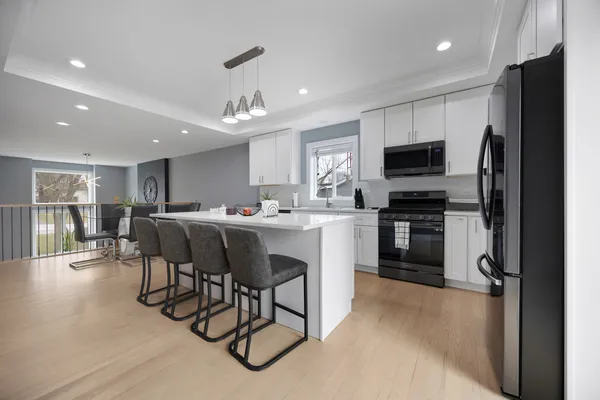 a kitchen with kitchen island a dining table chairs appliances and a counter top space