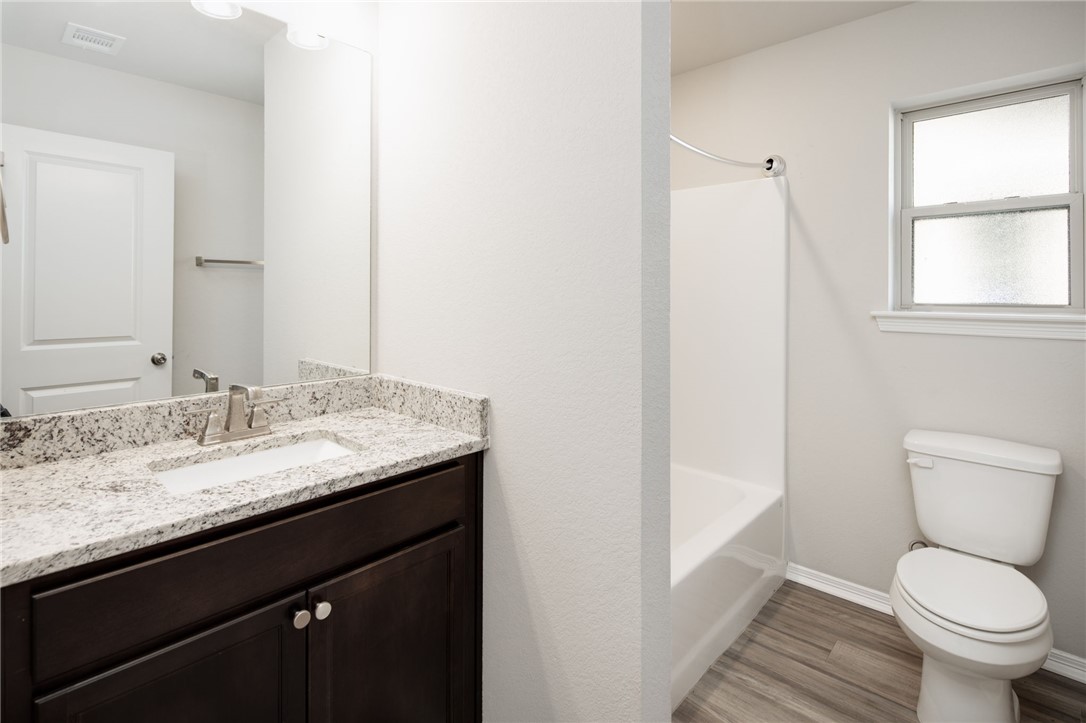 1203 High Street Navasota, TX 77868 - Photo 17 of 21 a bathroom with a granite countertop toilet a sink and a mirror