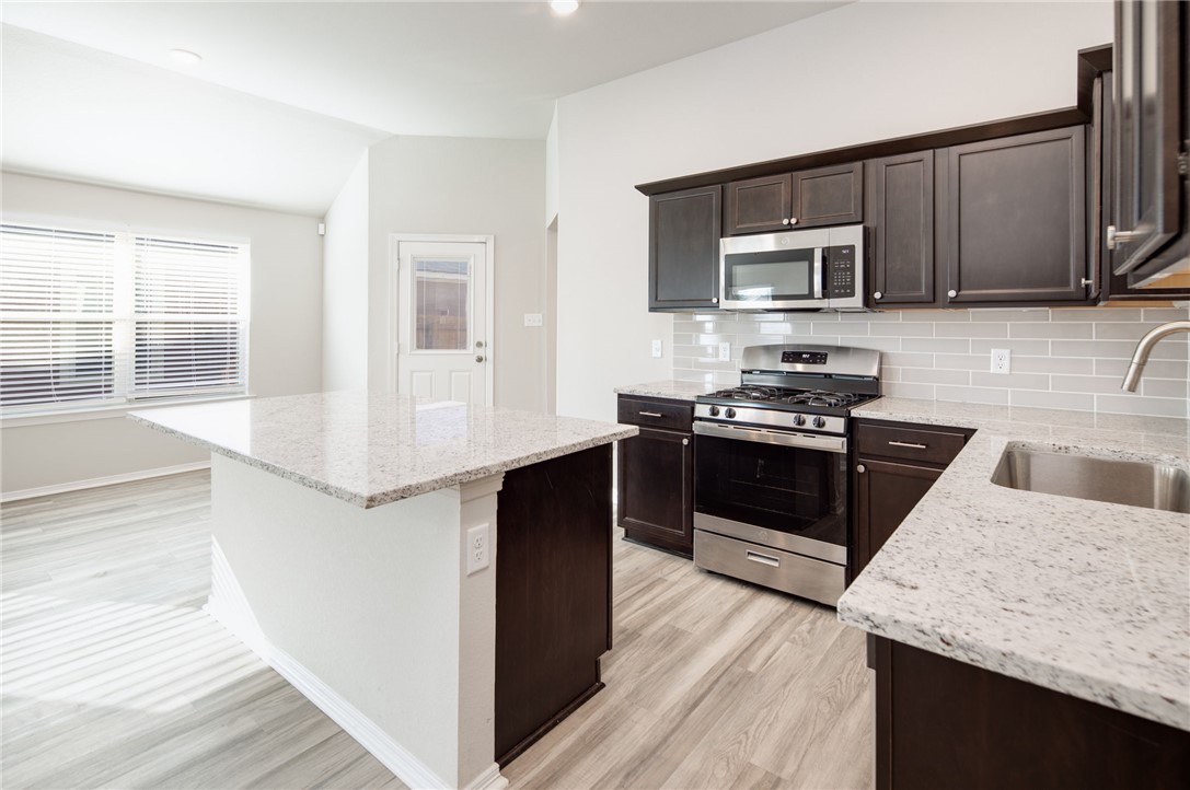 1203 High Street Navasota, TX 77868 - Photo 10 of 21 a kitchen with stainless steel appliances granite countertop a stove a sink and a microwave