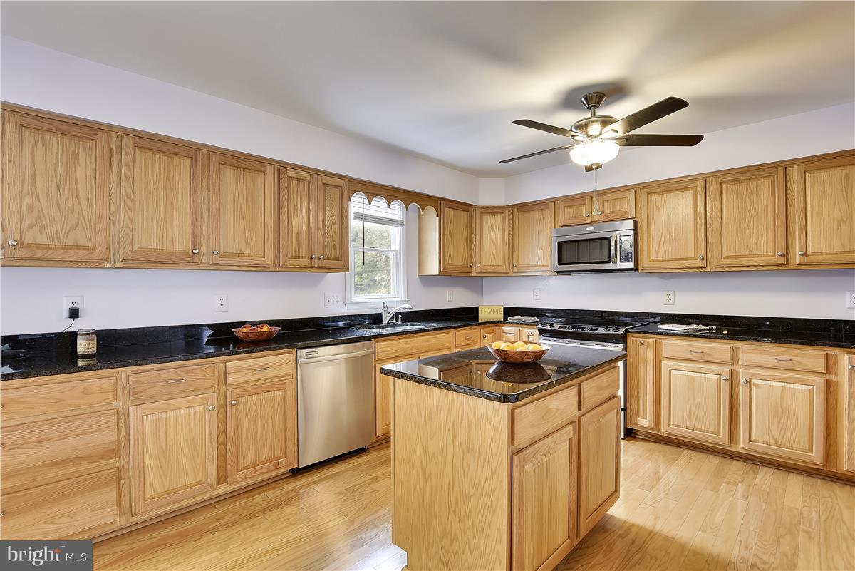 2313 Holly Spring Drive Silver Spring, MD 20905 - Photo 10 of 30 a kitchen with stainless steel appliances granite countertop white cabinets granite counter tops and a hard wood floors