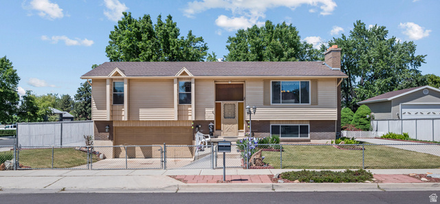 867 East 7905th Street South Sandy, UT 84094 - Photo 1 of 1 Split-level residence featuring a two-car garage, front yard with mature landscaping, and a chain-link fence