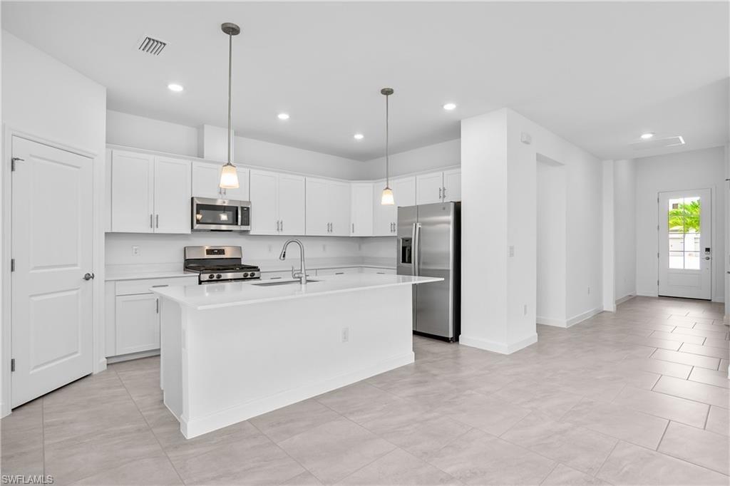 Kitchen featuring stainless steel appliances, a sink, light countertops, white cabinetry, and recessed lighting