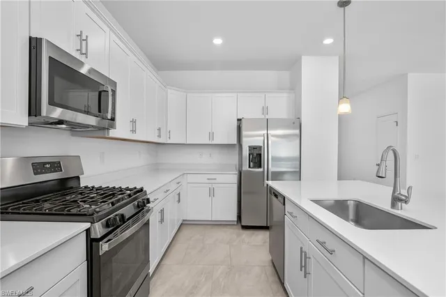 a kitchen with stainless steel appliances granite countertop a sink a stove top oven a refrigerator with white cabinets and stainless steel appliances