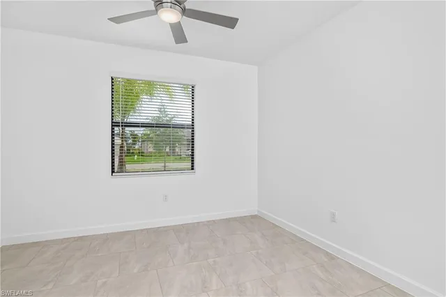 an empty room with a window and a fan