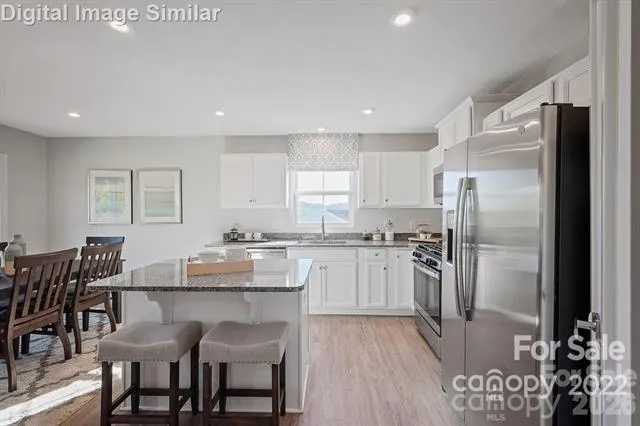 a kitchen with granite countertop a refrigerator and wooden cabinets