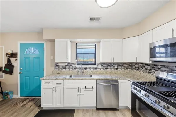 a kitchen with white cabinets and appliances