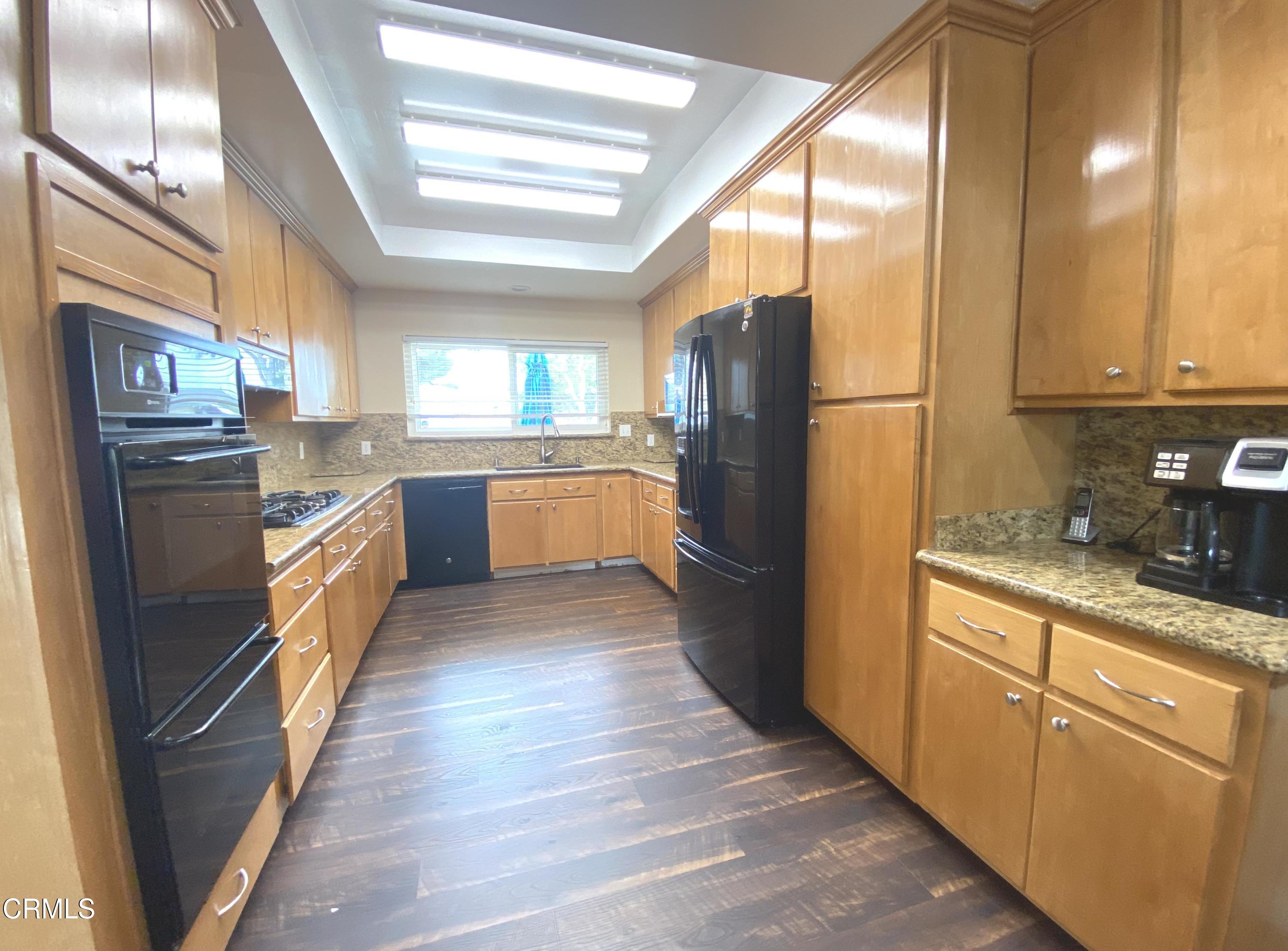 4520 Reeder Avenue Oxnard, CA 93033 - Photo 8 of 28 a kitchen with stainless steel appliances granite countertop a refrigerator a stove a sink and dishwasher with wooden floor