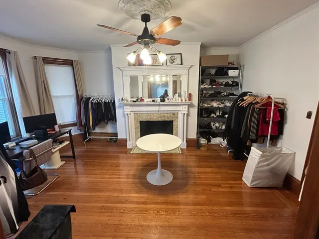 a view of a livingroom with furniture a fireplace wooden floor and windows