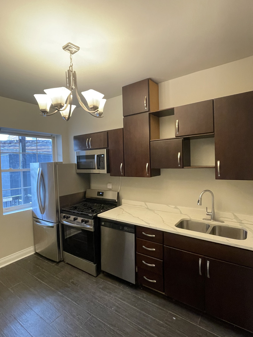 2826 West Lyndale Street, Unit 1 Chicago, IL 60647 - Photo 6 of 20 a kitchen with stainless steel appliances a sink cabinets and wooden floor