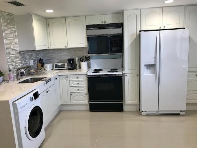 2871 North Ocean Boulevard, Unit V457 Boca Raton, FL 33431 - Photo 27 of 42 a kitchen with a refrigerator sink and cabinets