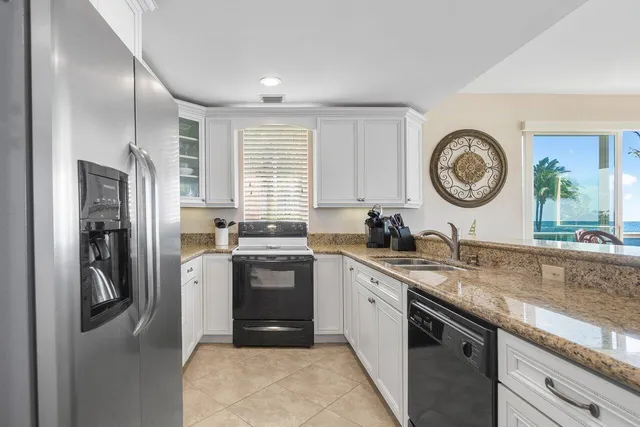 a kitchen with stainless steel appliances granite countertop a sink a stove a refrigerator and island