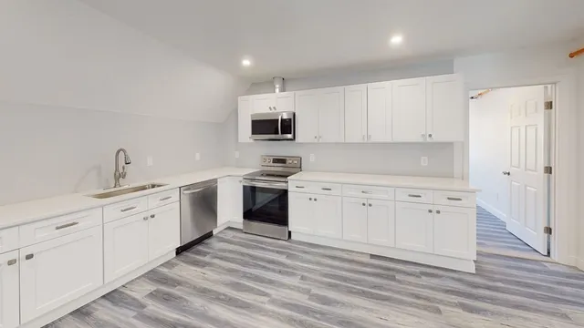 a kitchen with white cabinets white stainless steel appliances and sink