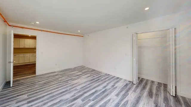 a view of an empty room with wooden floor and closet