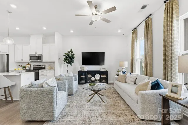 a living room with furniture a flat screen tv and a large window