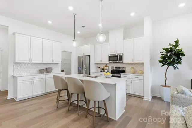 a kitchen with white cabinets and chairs