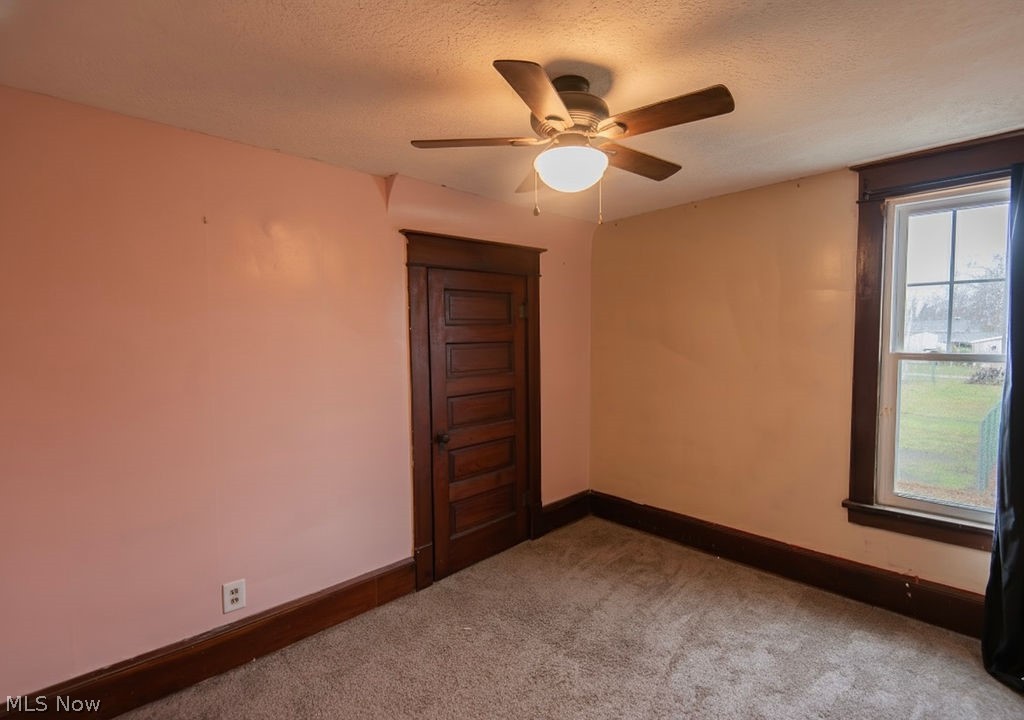 1195 South Johnson Road Sebring, OH 44672 - Photo 18 of 34 Empty room featuring a textured ceiling, dark carpet, and ceiling fan