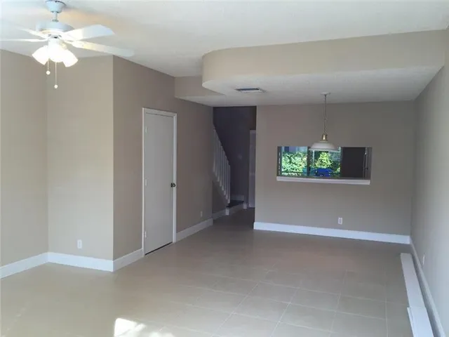 en empty room with windows and a ceiling fan