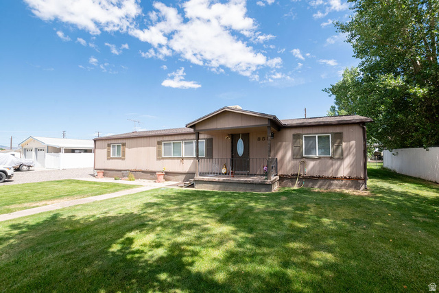 855 East 300 N Street Beaver, UT 84713 - Photo 5 of 44 Single-story residence featuring a covered front porch with metal railings, a manicured front lawn, and a paved walkway