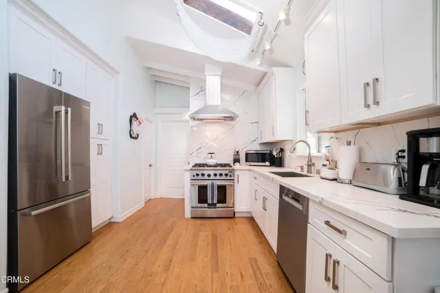 a kitchen with stainless steel appliances white cabinets and a refrigerator