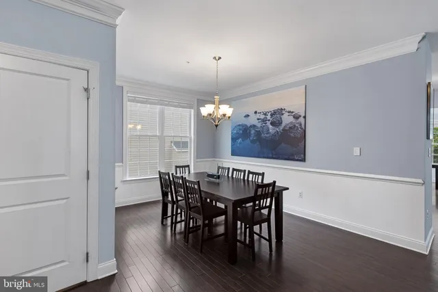 a kitchen with stainless steel appliances granite countertop a stove top oven a refrigerator a dining table and chairs with wooden floor