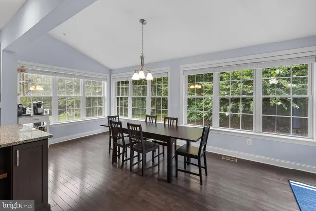 a kitchen with kitchen island a dining table chairs stainless steel appliances and cabinets