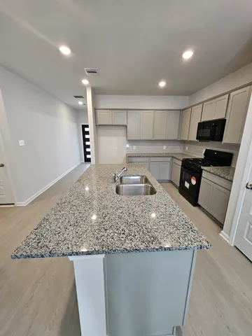 a kitchen with stainless steel appliances granite countertop a sink a stove and a refrigerator