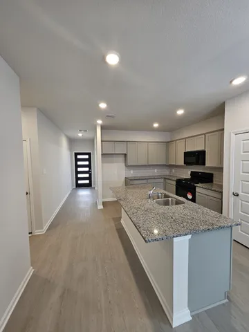 a kitchen with stainless steel appliances granite countertop a sink dishwasher and a refrigerator with wooden floor