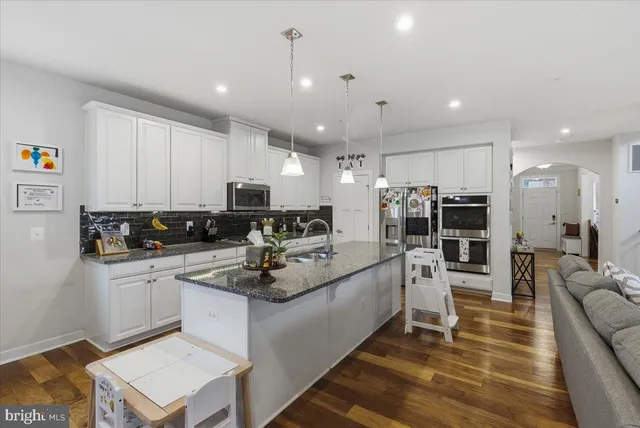 a kitchen with stainless steel appliances kitchen island sink stove refrigerator and cabinets