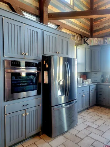a kitchen with stainless steel appliances granite countertop a refrigerator a stove and a sink with wooden cabinets