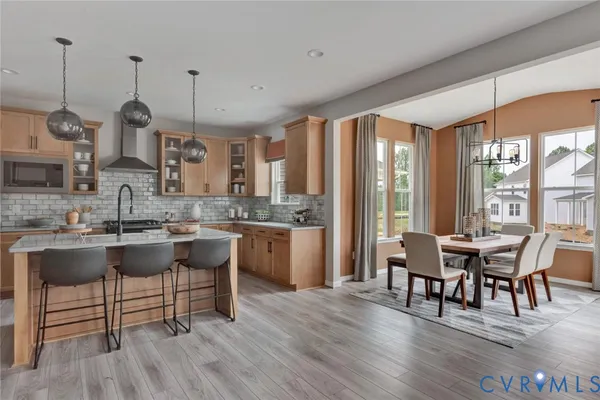 a dining room with stainless steel appliances granite countertop a kitchen island a stove and a wooden floors
