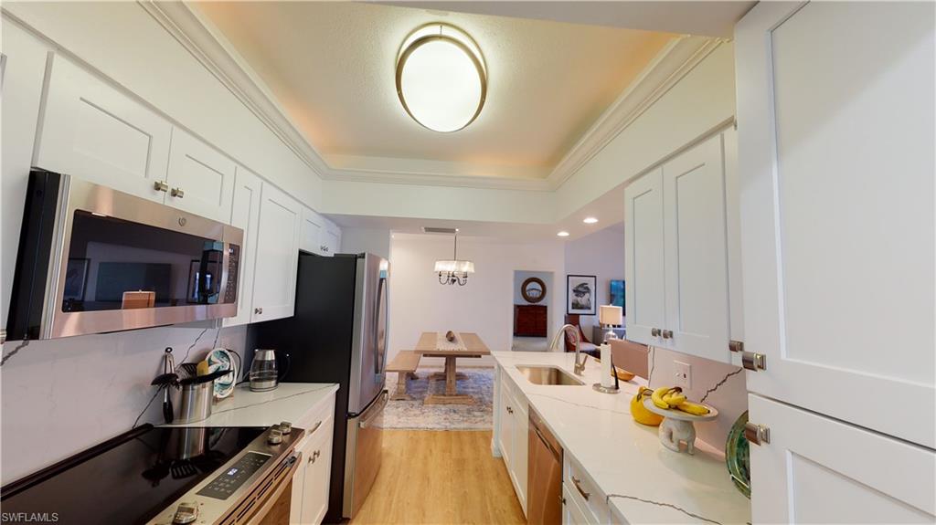 792 Willowbrook Drive, Unit 408 Naples, FL 34108 - Photo 3 of 7 a view of a kitchen with kitchen island granite countertop a sink and a stove top oven with wooden floor