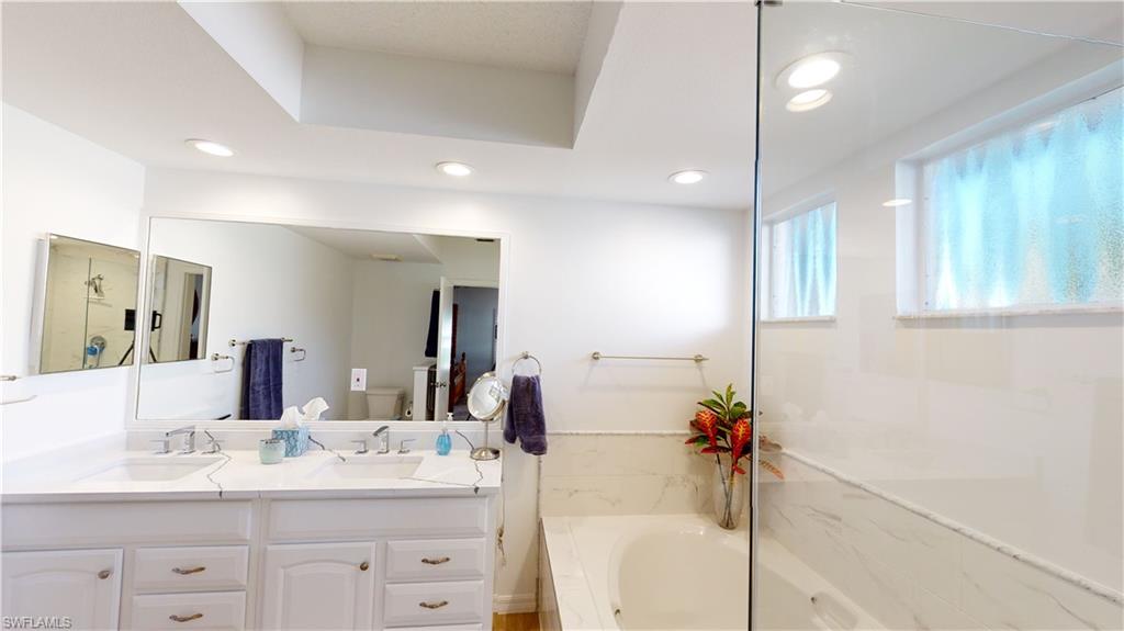 792 Willowbrook Drive, Unit 408 Naples, FL 34108 - Photo 5 of 7 a bathroom with a double vanity sink a mirror and a shower
