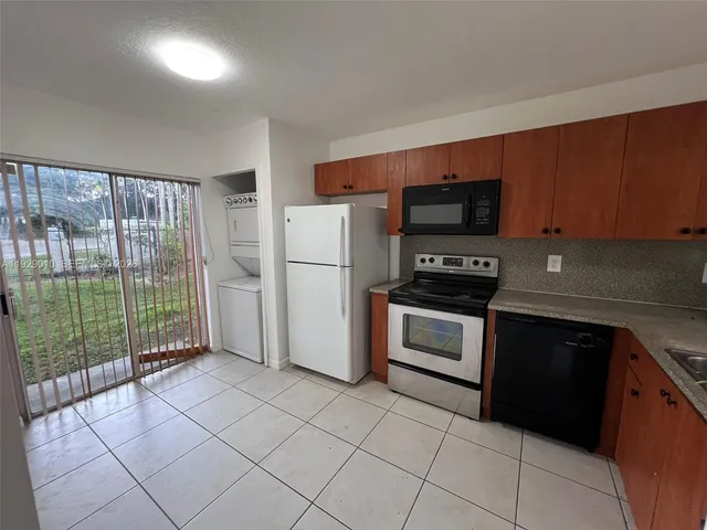 a kitchen with granite countertop a refrigerator a stove a microwave and a sink