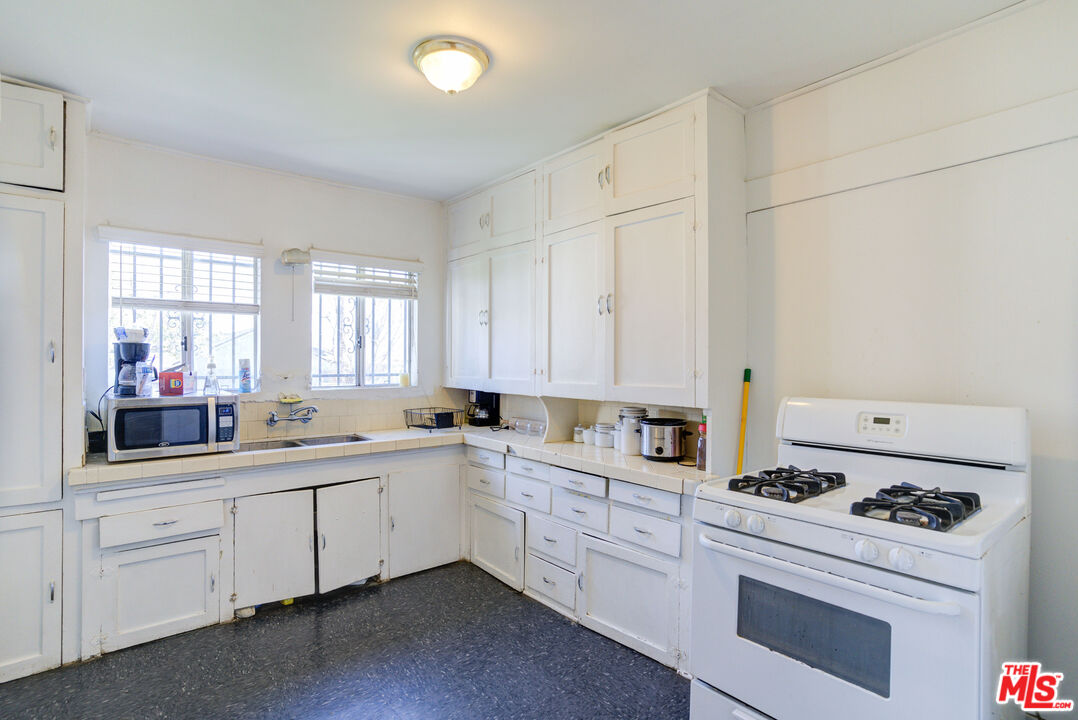 2404 Virginia Road Los Angeles, CA 90016 - Photo 10 of 21 a kitchen with white cabinets sink and white appliances