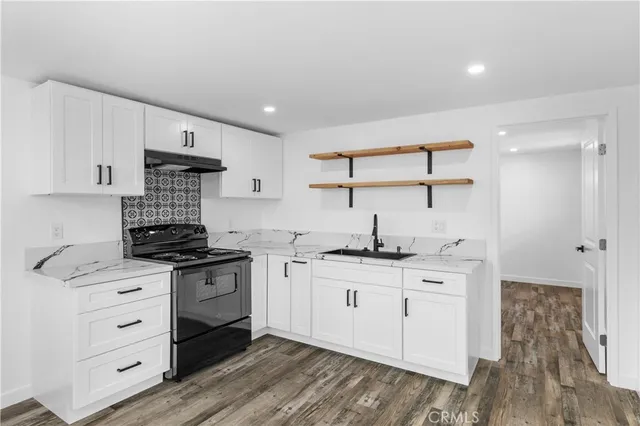 a kitchen with granite countertop a sink cabinets and wooden floor