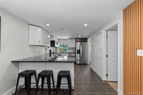 a kitchen with stainless steel appliances granite countertop a table chairs sink and cabinets
