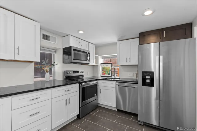 a kitchen with refrigerator a microwave a sink and cabinets