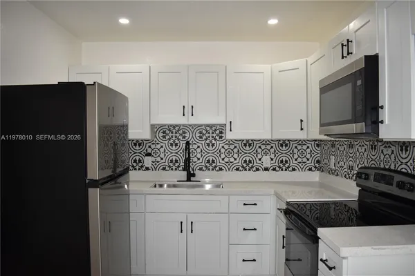a kitchen with granite countertop a refrigerator and a sink