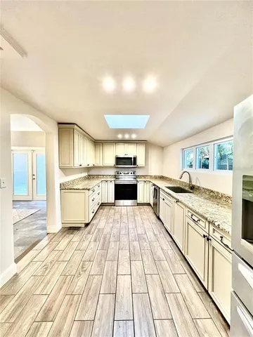 a view of a kitchen with wooden floor and electronic appliances