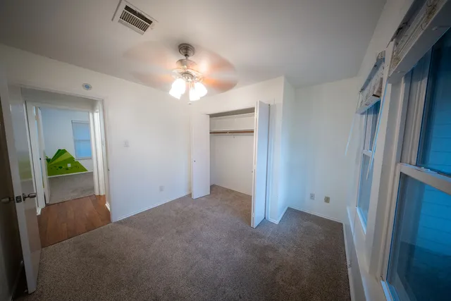 a view of empty room with wooden floor and fan