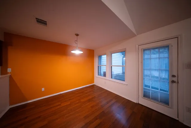 a view of an empty room with wooden floor and windows