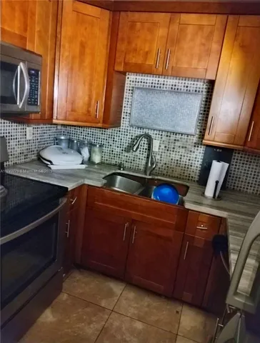 a kitchen with granite countertop a sink cabinets and a stove top oven