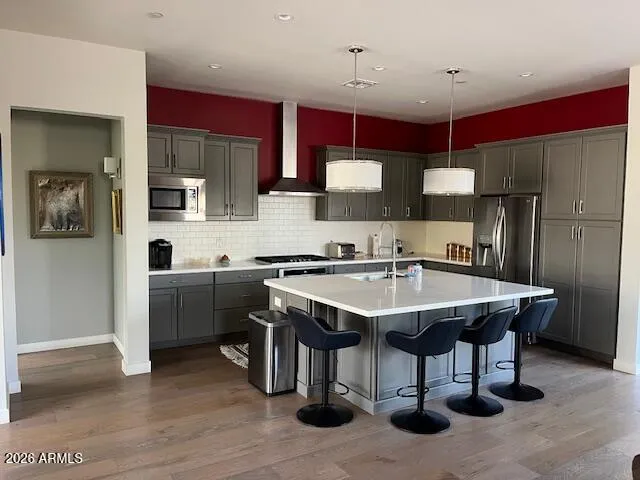 a kitchen with stainless steel appliances kitchen island granite countertop a sink dishwasher a refrigerator and a stove with wooden floor