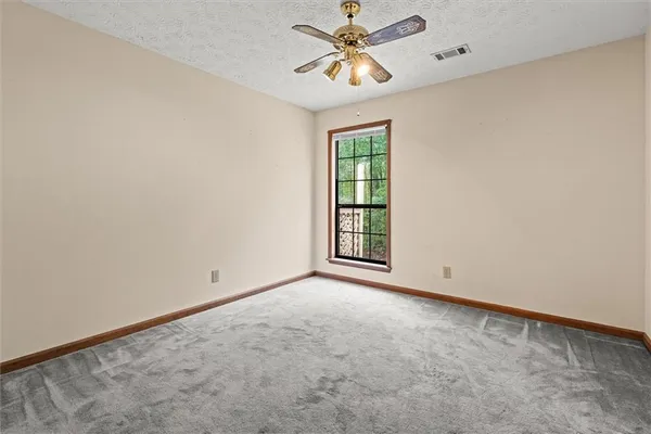 an empty room with windows and fan
