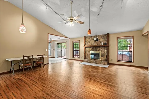 an empty room with wooden floor fireplace and windows