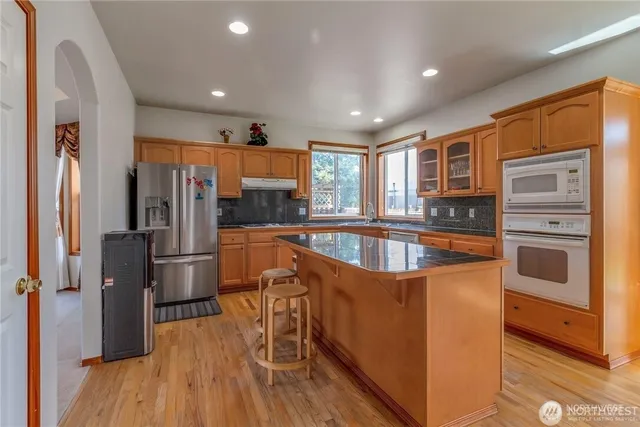 a kitchen with stainless steel appliances granite countertop a sink a stove and a wooden floors
